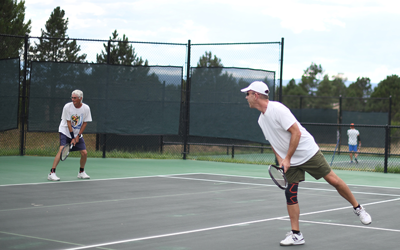 Two men playing tennis in the Village at Castle Pines gated community.